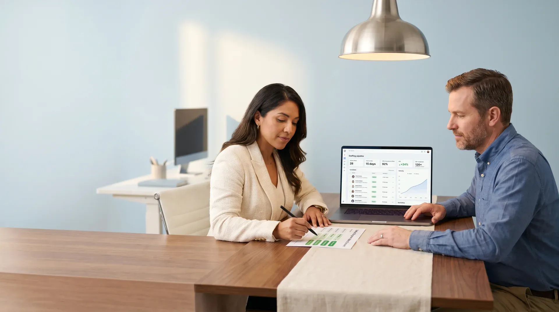 A hiring manager reviewing a fragmented AI candidate pipeline on a laptop, visible workload pressure, natural desk light A hiring manager reviewing a fragmented AI candidate pipeline on a laptop, visible workload pressure, natural desk light
