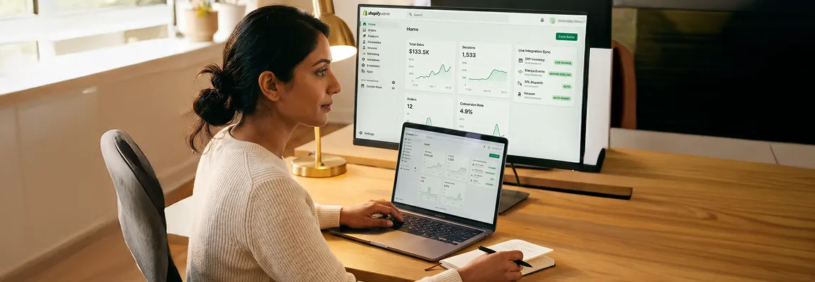 Shopify merchant at desk reviewing live integration sync dashboard showing ERP and Klaviyo connections in real time, warm morning office light Shopify merchant at desk reviewing live integration sync dashboard showing ERP and Klaviyo connections in real time, warm morning office light